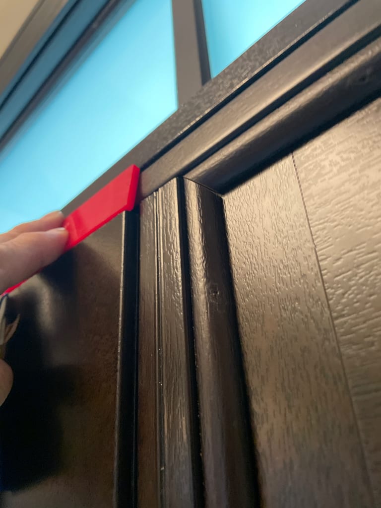 A 3/16-inch feeler gauge showing how far the slab protrudes from the door frame at the top latch corner. UTS ServicePros field photo.